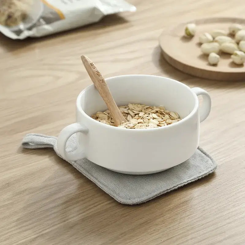 Light gray cotton linen coaster set with handle displayed under a white ceramic bowl with rolled oats and wooden spoon, decorbites cotton linen coaster