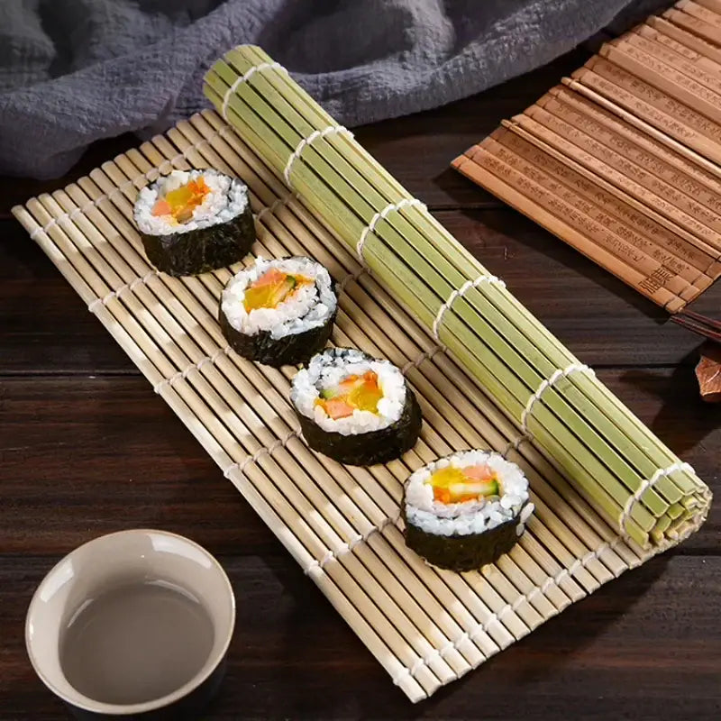 Four sushi pieces with salmon and cucumber on a light green bamboo sushi rolling mat set for kitchen diy use