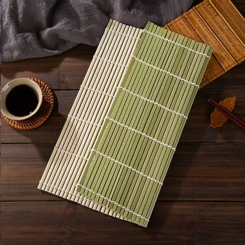 Two bamboo sushi rolling mats in natural beige and light green with white string bindings in a rolling mat set