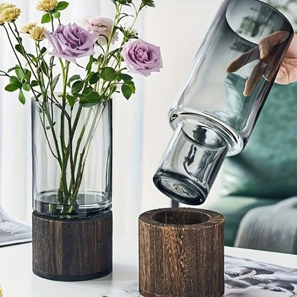 Tall clear glass vase with dark wood base holding purple and yellow roses for living room table decoration
