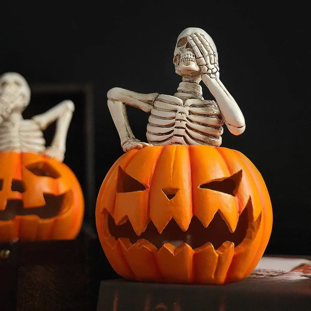 A white skeleton figurine with detailed ribs and hand gesture sits atop a vibrant orange skull pumpkin skeleton sculpture