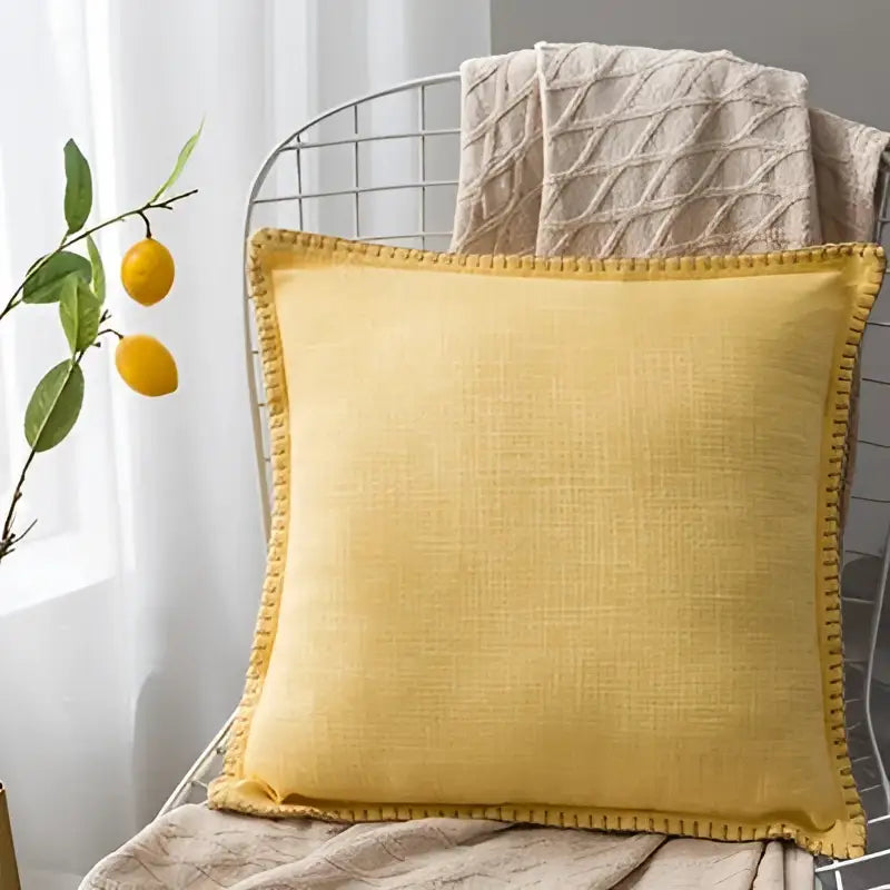 Yellow linen fringe cushion cover with textured rustic finish and decorative pom-pom trim for living room decorbites