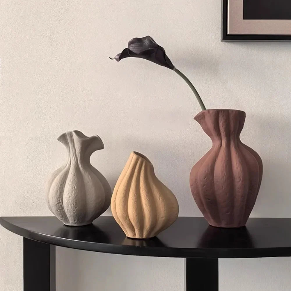 Three muted earth tone ceramic vases with textured organic shapes sitting on a dark table for modern boho decor
