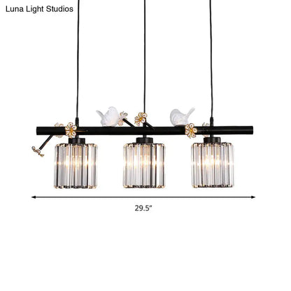 Black wrought iron pendant light with three clear crystal cylinder shades and white porcelain bird accents for island lighting