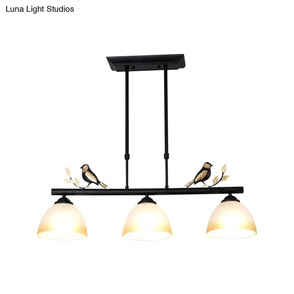 Black wrought iron pendant light with three milky glass shades and decorative bird motifs on central bar