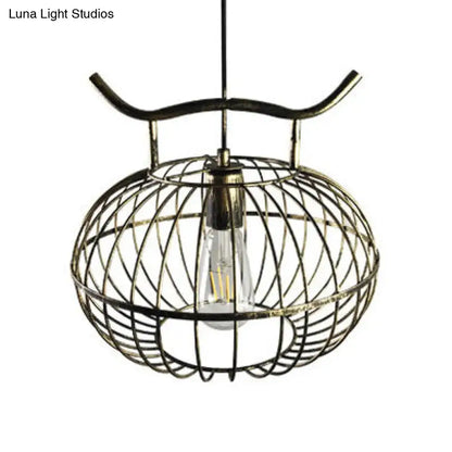 Antique brass cage-style pendant light with visible edison bulb in rust aged brass finish with lantern design