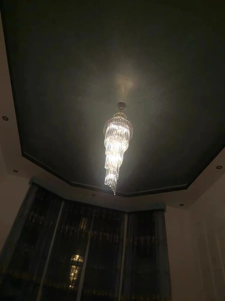A long crystal staircase gold chandelier with a metallic frame and clear glass prisms for hotel hall decor