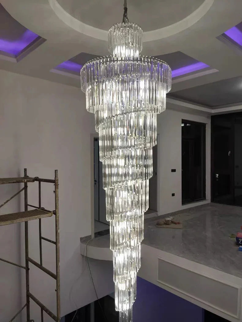 Long crystal staircase gold chandelier with cascading glass rods hanging in an elegant hotel hall interior