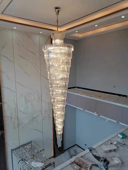 A long crystal staircase gold chandelier with cascading tiers and metallic finish for hotel hall and luxury decor