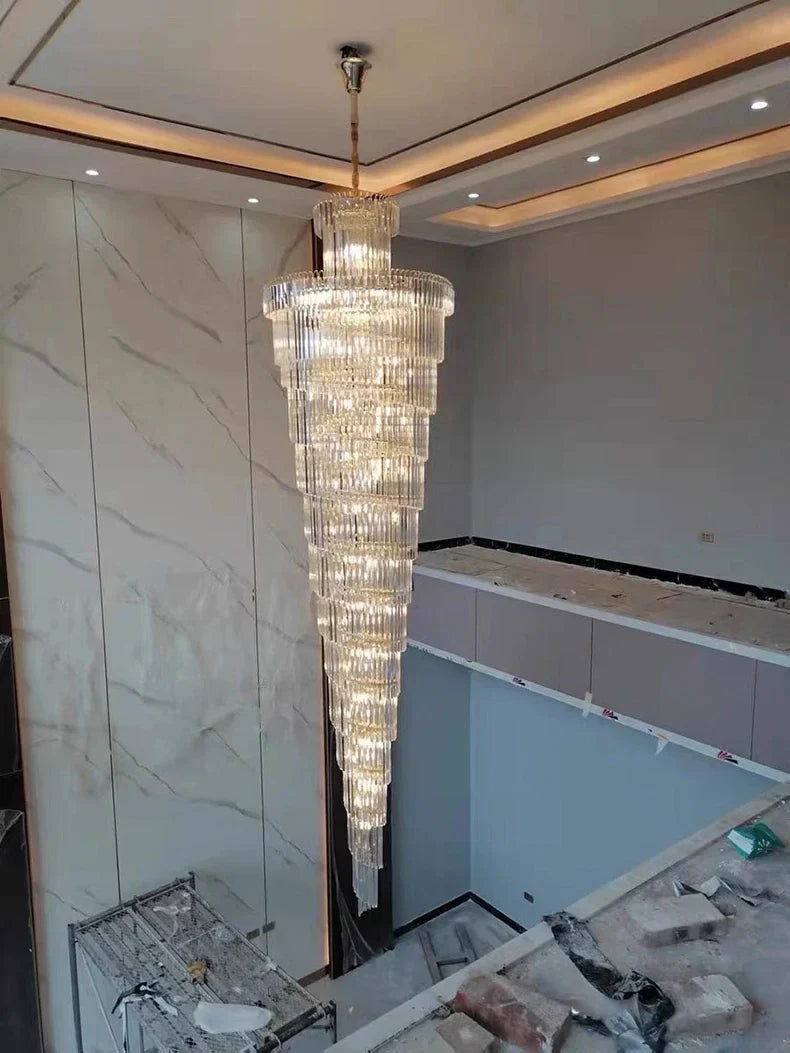 A long crystal staircase gold chandelier with cascading tiers and metallic finish for hotel hall and luxury decor