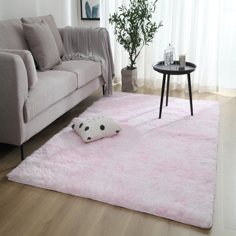 Pink fluffy rug with white polka dots and a textured edge, likely made of synthetic fur or plush material.