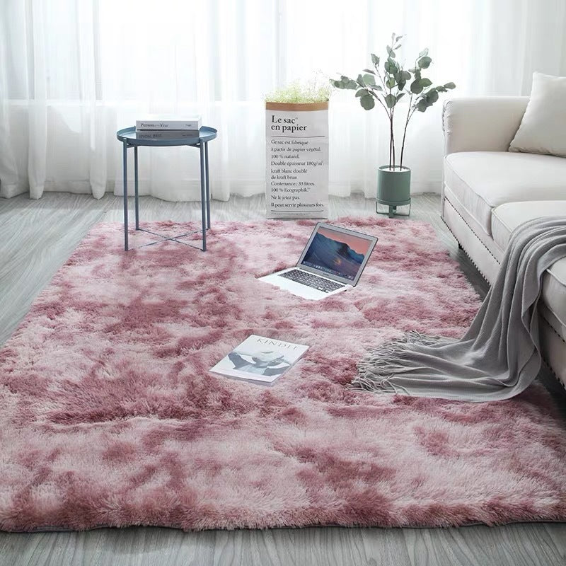 Pink fluffy rug with a tie-dye pattern and soft texture.