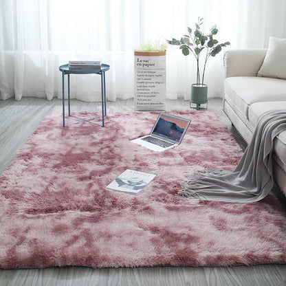 Pink fluffy rug with a tie-dye pattern and soft texture.