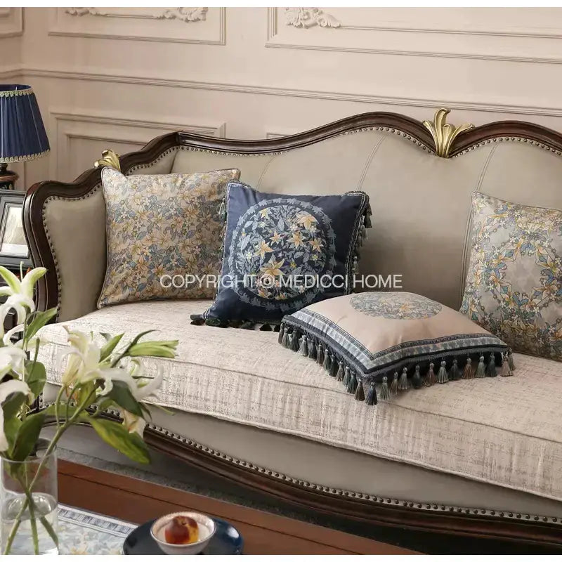 Beige upholstered sofa with dark wood frame and gold accents featuring decorbites camellia floral velvet cushion cover with tassels