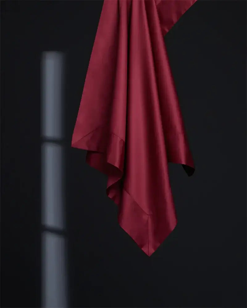 A luxurious burgundy red egyptian cotton bedding set featuring rich satin fabric against a dark background