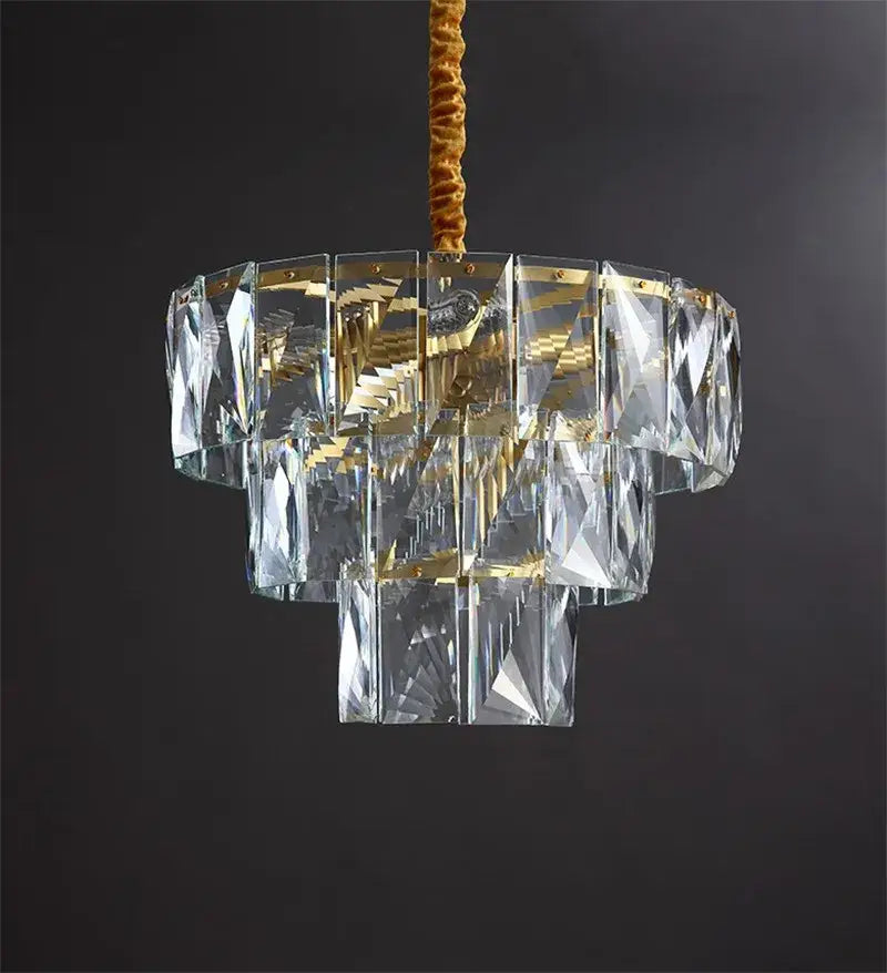 A tiered luxe gold steel crystal pendant light with gold-toned metal accents and a textured brown cord suspension