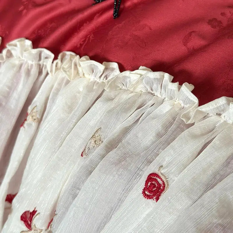 White sheer egyptian cotton lace bedding set featuring lace ruffles with red and gold embroidered floral motifs