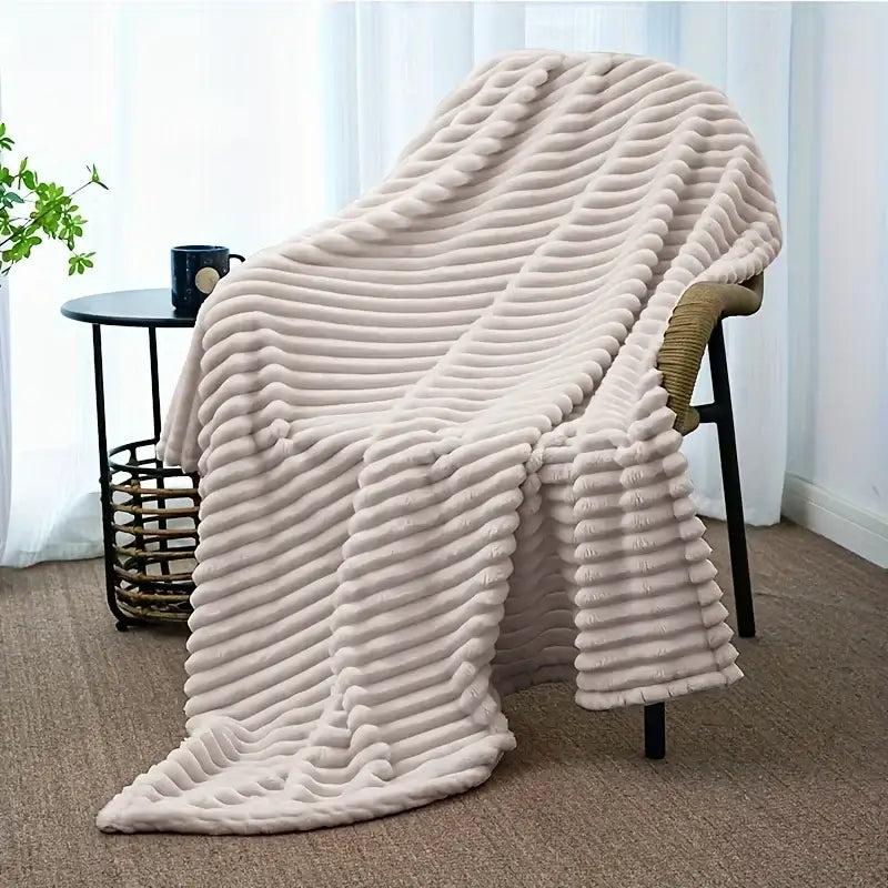A cream-colored ribbed flannel throw blanket draped over an armchair for bedroom plush decor