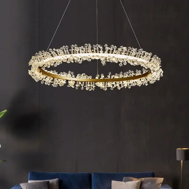 A modern crystal gold ring led chandelier with gold-toned metal frame and clear crystal droplets for living room decor