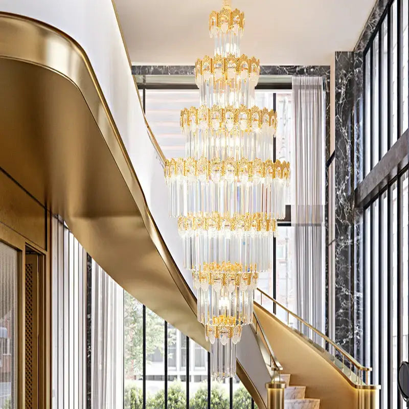 A luxurious gold and clear decorbites crystal staircase chandelier with multi-tiered metalwork and crystal prisms hanging from a ceiling