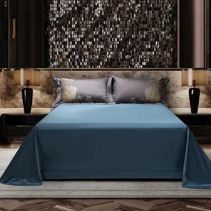 A sleek solid blue satin bedspread with glossy finish drapes over mattress in luxurious gray gold jacquard egyptian cotton bedding set