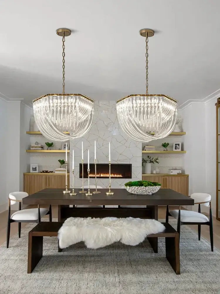 Two elegant crystal-encrusted chandeliers with gold-toned frames hang above a decorbites black stainless steel dining table light