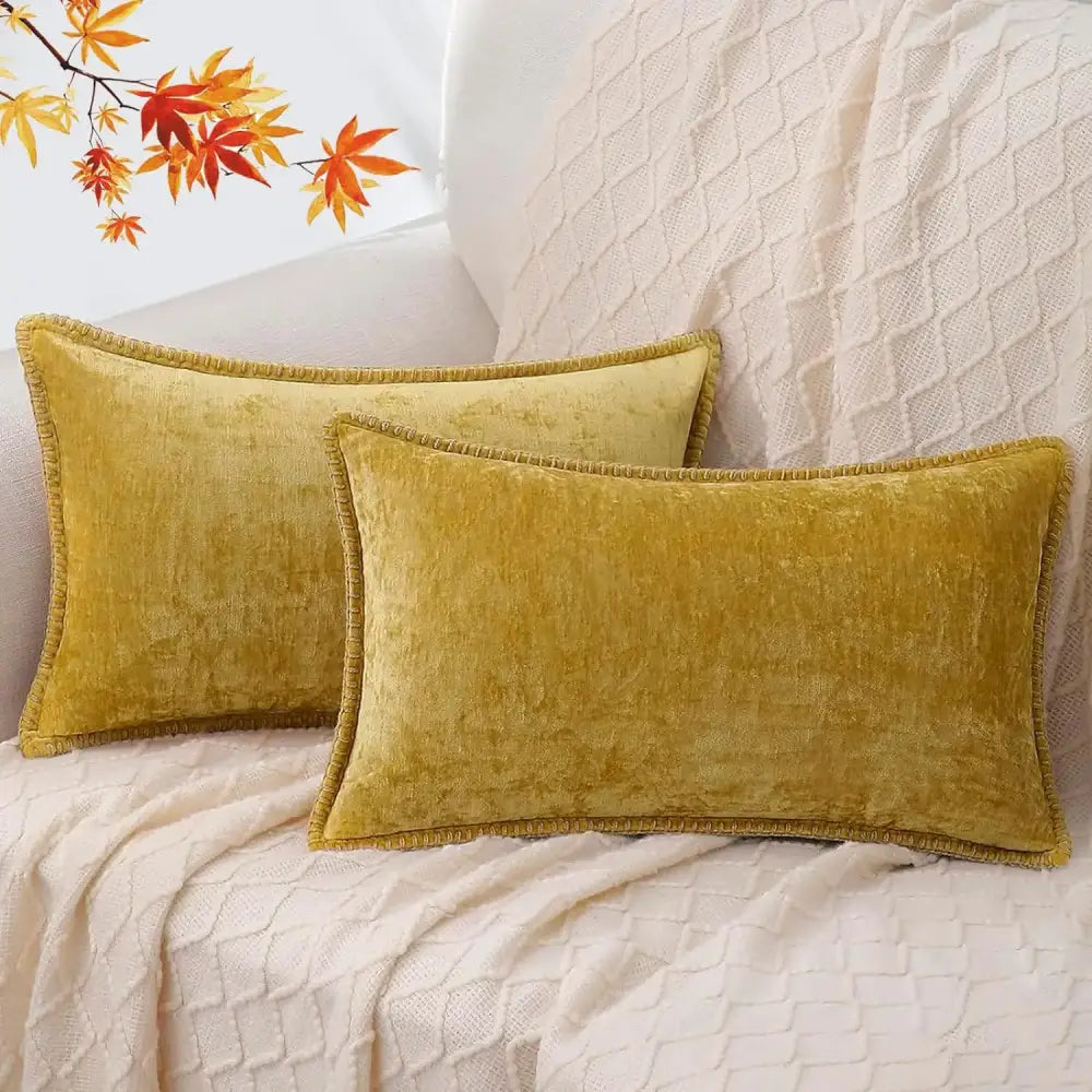 Two mustard-yellow velvet rectangular pillows with fringed edges on white blanket complement decorbites blue chenille cushion covers