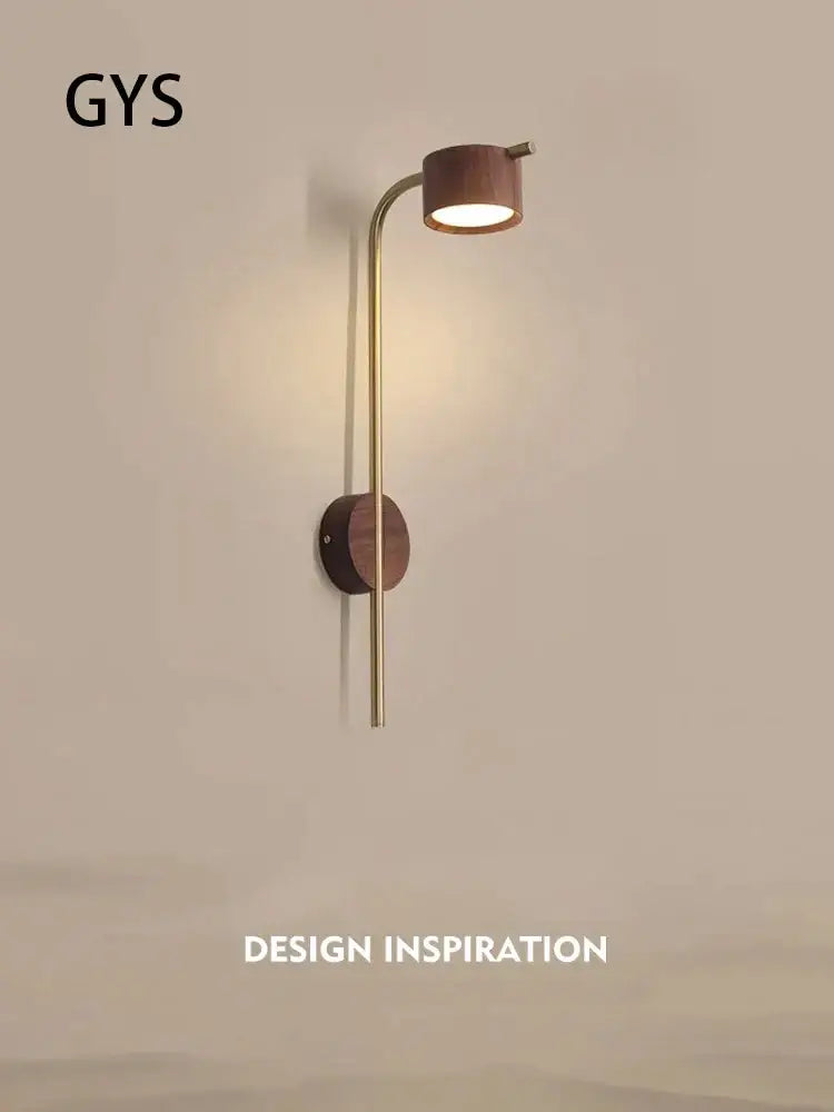 A sleek brass wall lamp with curved arm and black walnut wood accents featuring an adjustable reading light head