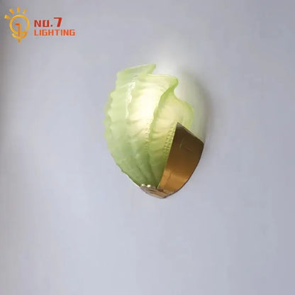 Luxury brass glass shell wall lamp featuring a translucent green leaf-shaped glass with a gold decorbites brass glass base