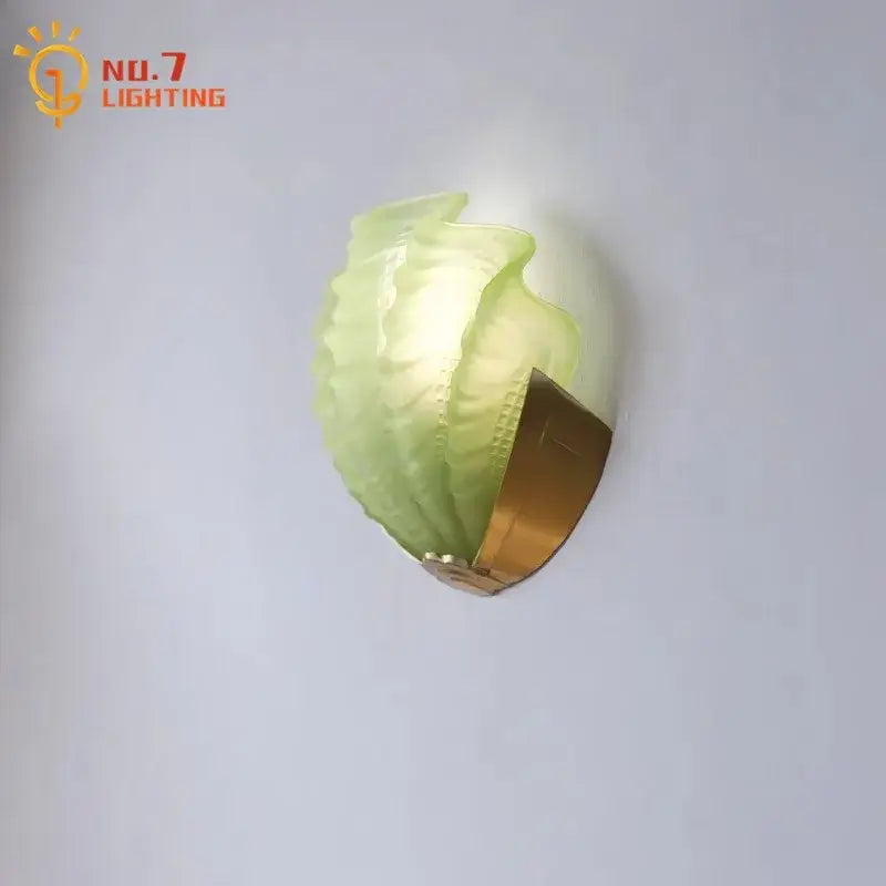 Luxury brass glass shell wall lamp featuring a translucent green leaf-shaped glass with a gold decorbites brass glass base