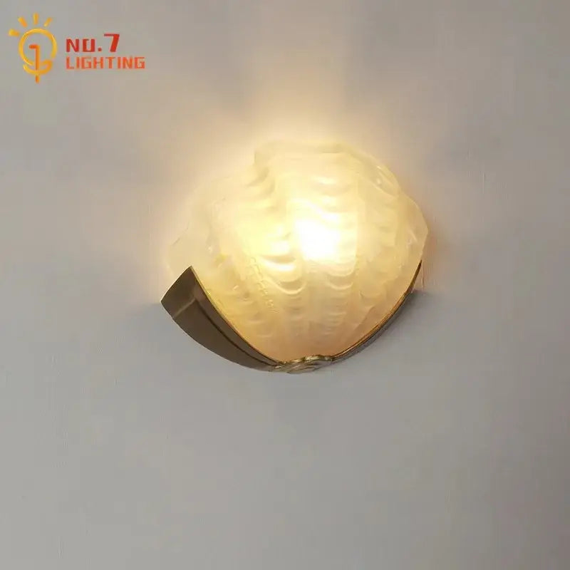 Warm-toned brass glass shell wall lamp with textured glass and brass-finished base for bedroom or living room decorbites brass glass