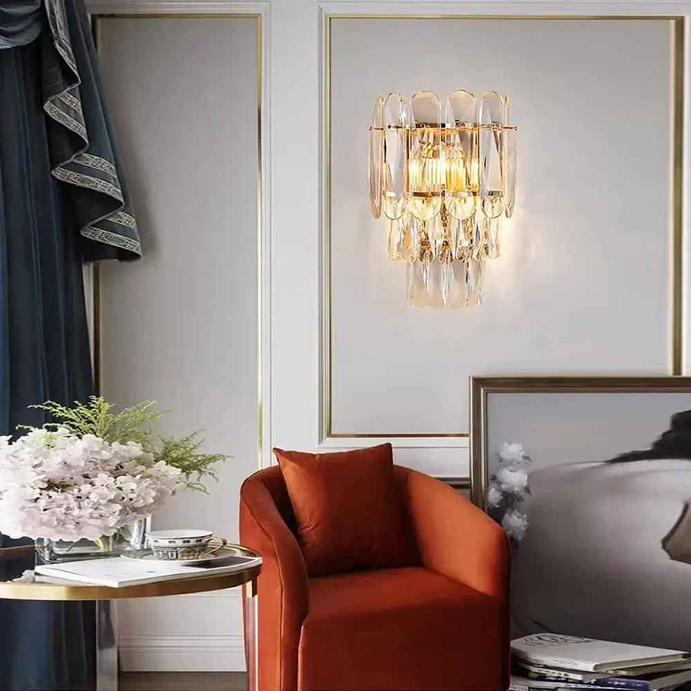 A gold-toned wall lamp with cascading clear crystal prisms for luxury decorbites crystal led wall lighting