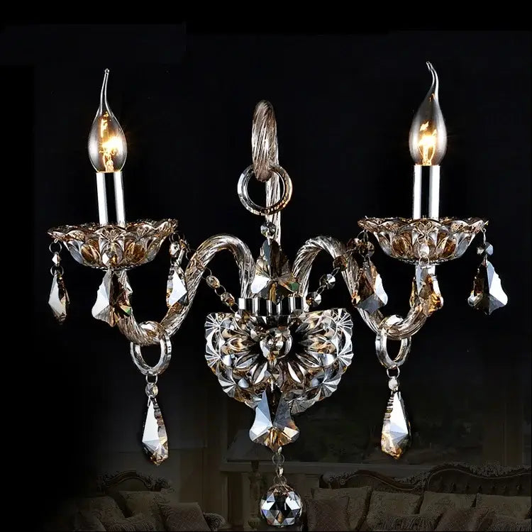 Elegant clear crystal wall lamp with silver metal arms and three candle-style bulbs by decorbites clear crystal design