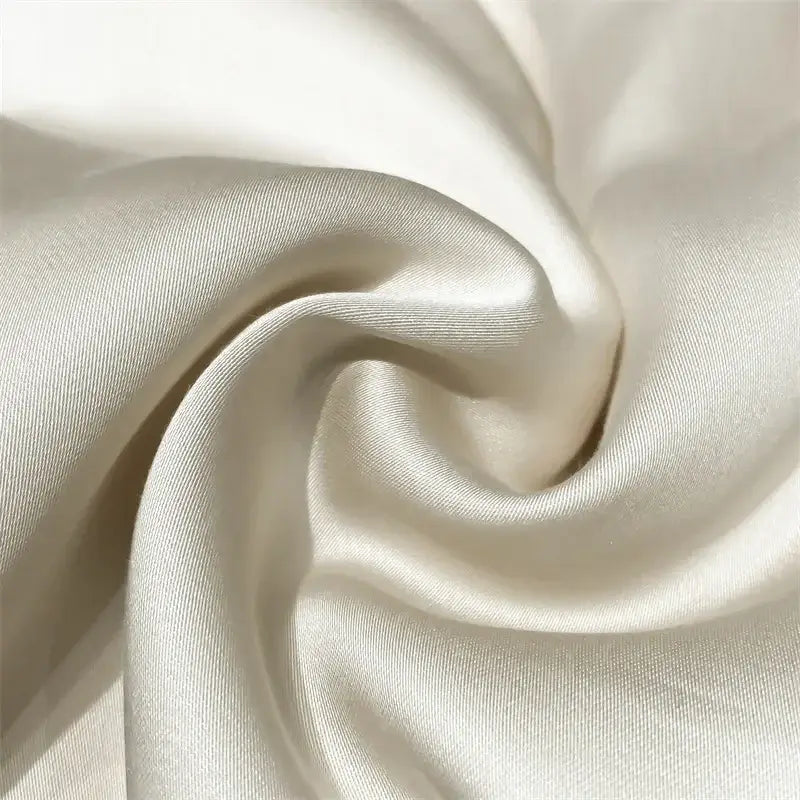 Cream-colored satin fabric with smooth glossy finish and subtle sheen in luxury cream and black ice silk embroidered quilt set
