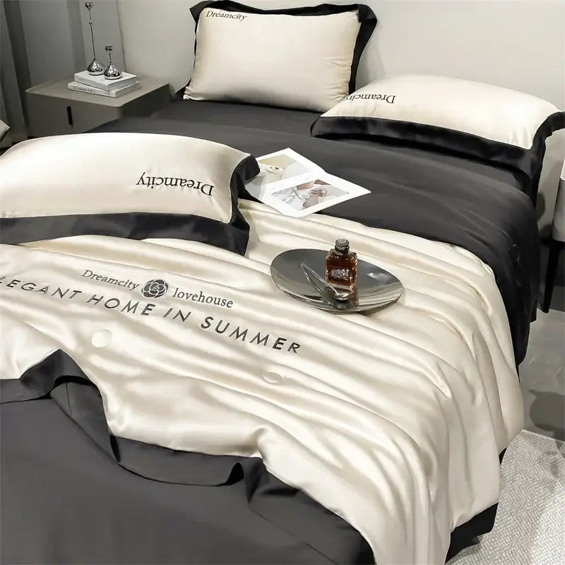 Luxury cream and black ice silk embroidered quilt set featuring a cream satin duvet cover with black trim and dreamcity branding