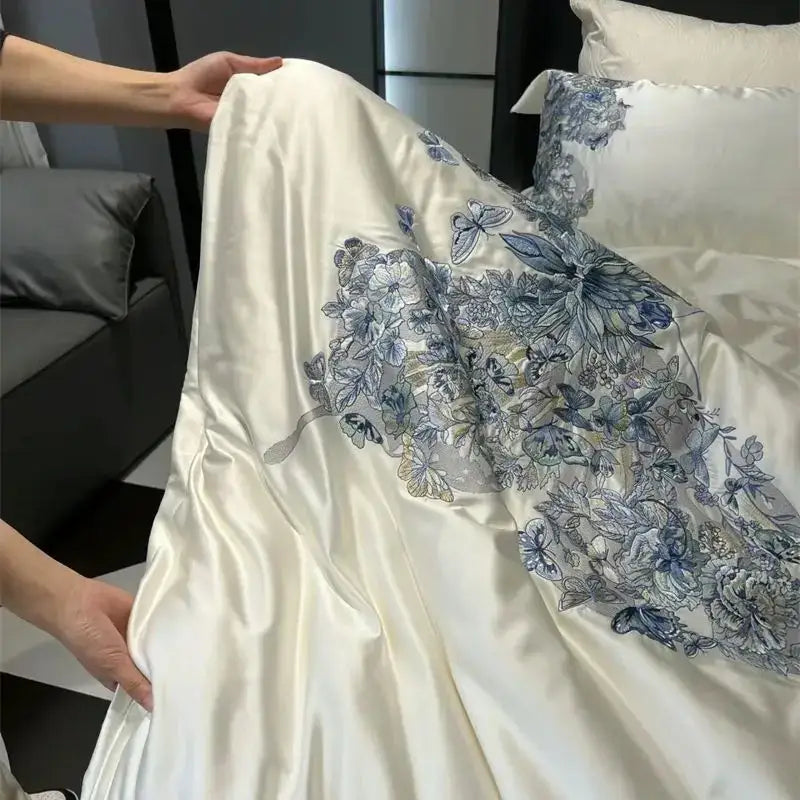 Cream-colored satin duvet cover with intricate blue and gray butterfly flowers embroidery in luxury bedding set
