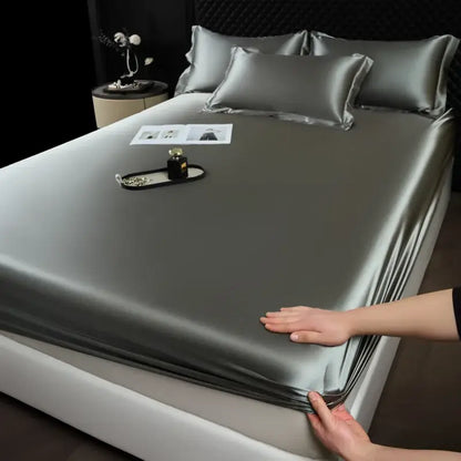 Silk-like gray satin fitted sheet set with matching pillowcases elegantly draped over a modern bed for luxury bedroom use