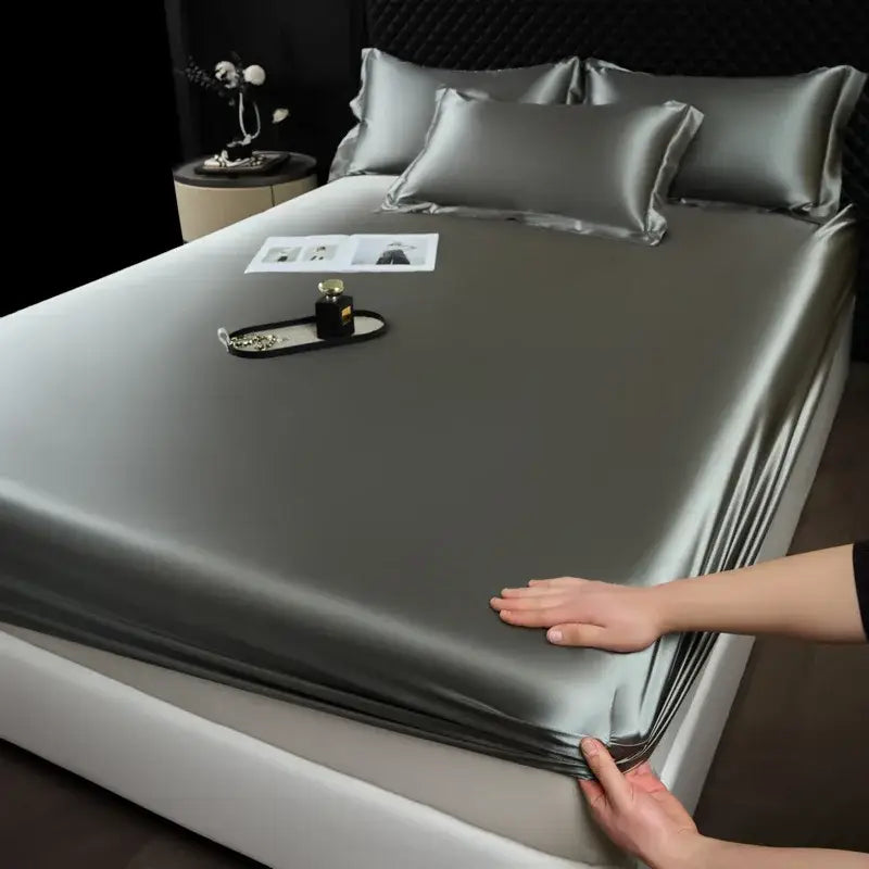 Silk-like gray satin fitted sheet set with matching pillowcases elegantly draped over a modern bed for luxury bedroom use