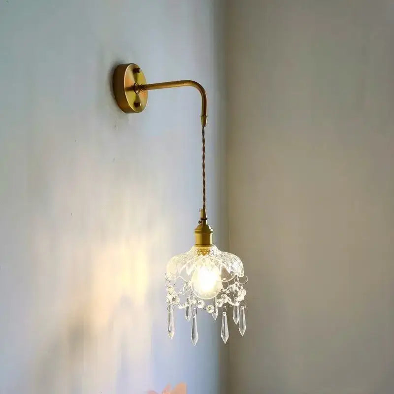 A delicate brass luxury crystal copper led wall sconce with curved arm and dangling crystals for bedroom lighting
