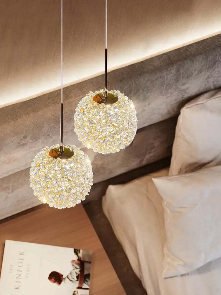 Two gold-toned decorbites crystal ball pendant lights with faceted amber crystal spheres for luxury bedroom lighting