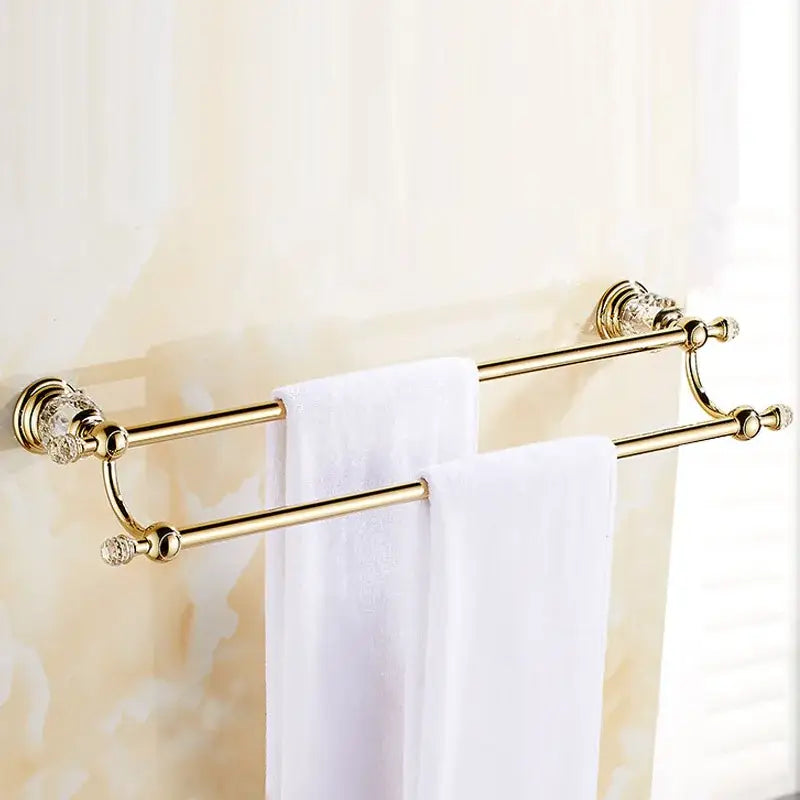 Luxury gold and crystal bath hardware double towel rack with crystal embellishments and two white towels hanging