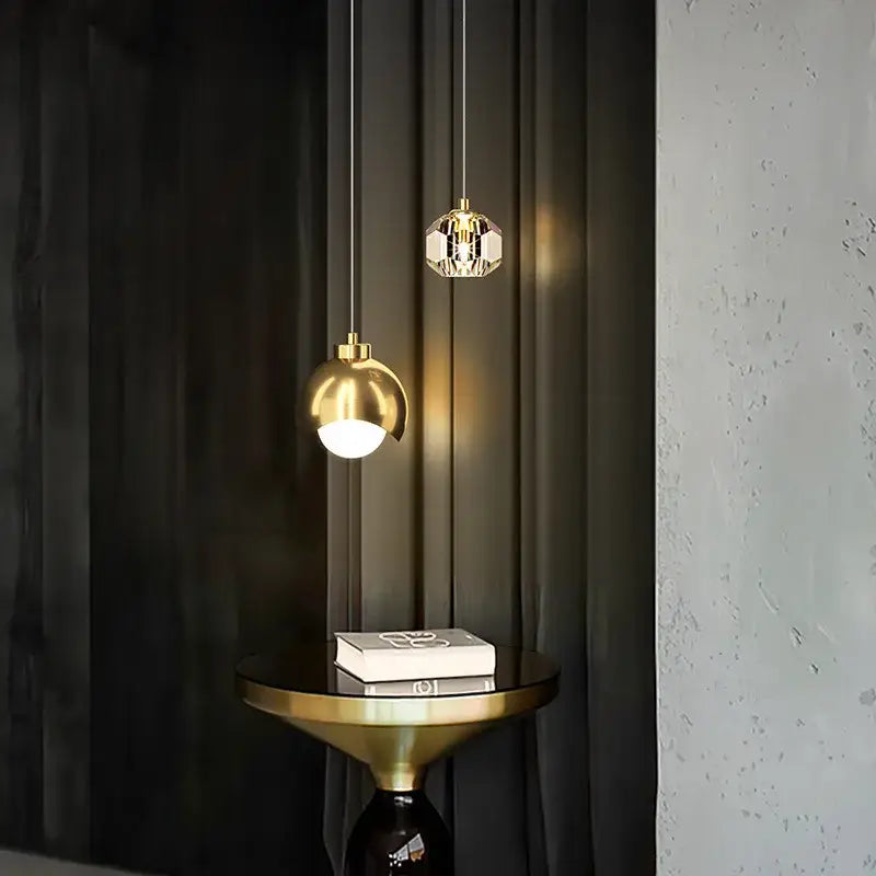 Two elegant pendant lights feature a polished gold decorbites glass ball and a faceted crystal glass ball pendant light