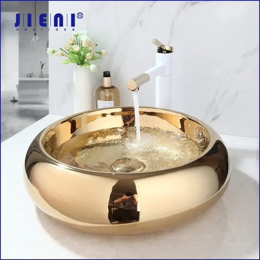 Gold-colored glossy ceramic vessel sink with modern design paired with luxury bath mixer set for bathroom use