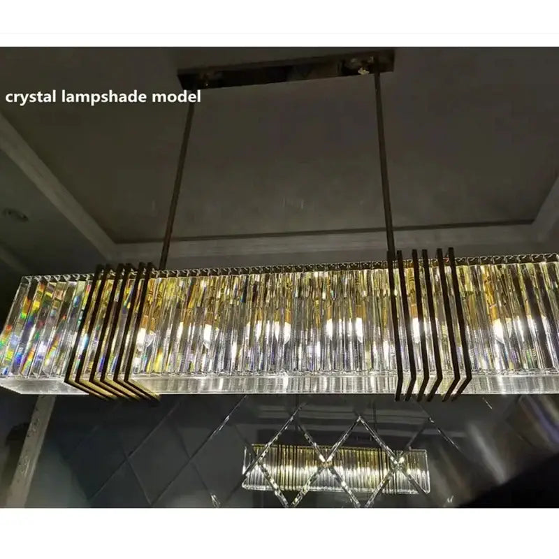 A modern luxury gold crystal rectangular pendant light with clear faceted prisms for dining room decorbites gold lustre
