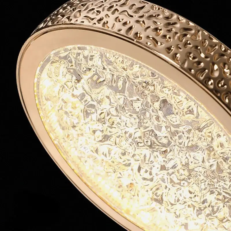 Luxury gold crystal ring pendant light with textured hammered metal frame and bubble-patterned illuminated glass panel