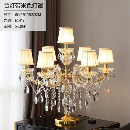 Elegant gold-toned crystal table light with multiple cream fabric shades and dangling faceted glass teardrops chandelier lamp