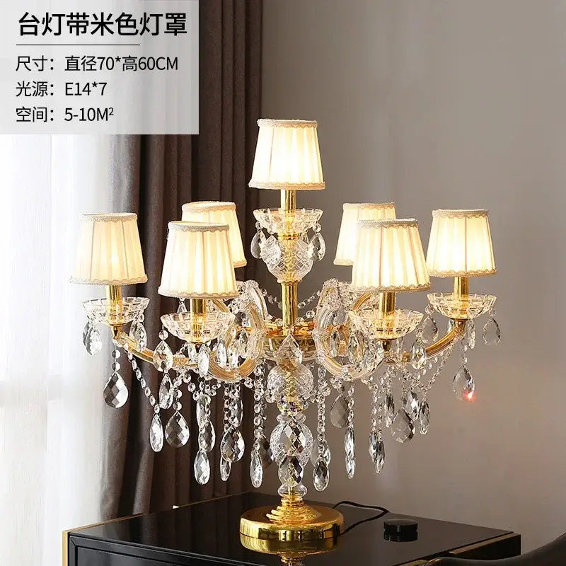 Elegant gold-toned crystal table light with multiple cream fabric shades and dangling faceted glass teardrops chandelier lamp