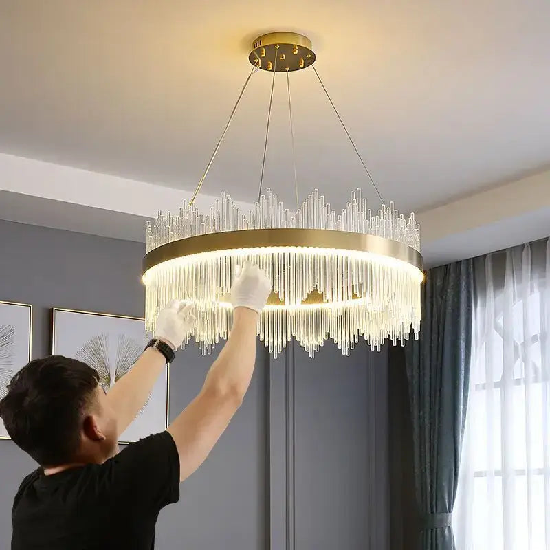 Modern gold-toned decorbites crystal led chandelier with clear glass prisms and circular frame for dining room lighting