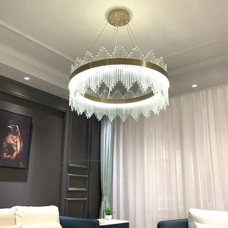 Modern gold-toned decorbites crystal led chandelier with cascading clear crystal strands and circular frame for dining room light