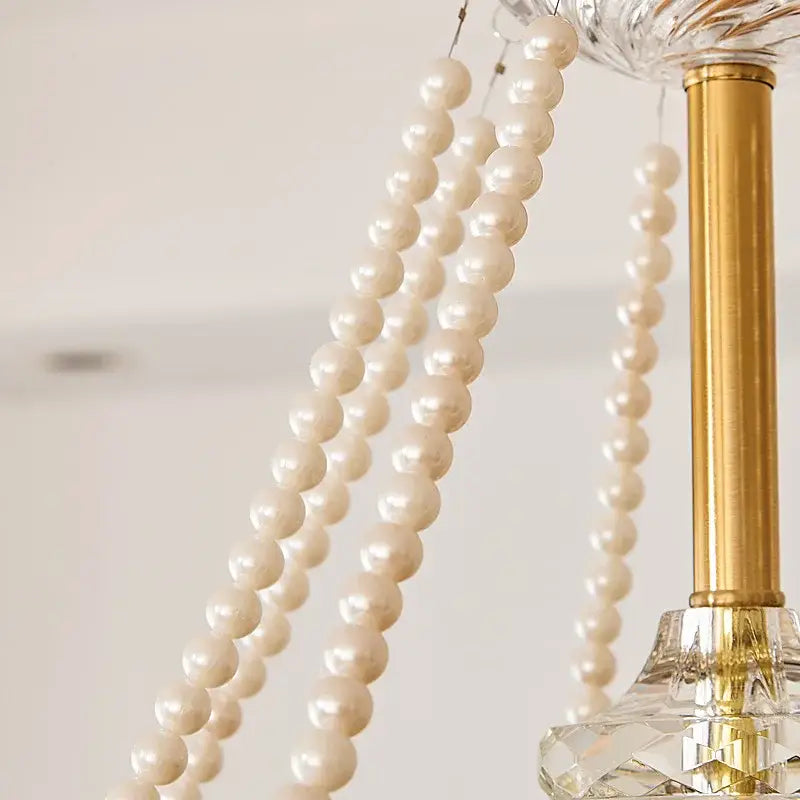 Cream-colored pearl strands hang elegantly from a gold-toned decorbites crystal led chandelier pendant light